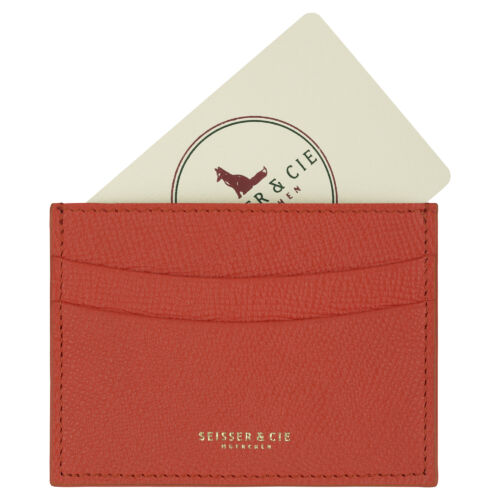 Ein orangenes, strukturiertes Kreditkarten-Etui (Orange) mit der goldenen Aufschrift "SEISSER & CIE MÜNCHEN" hält eine cremefarbene Karte mit rotem Fuchs-Logo und kreisförmigem Text.