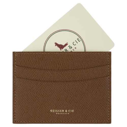 Ein cognacfarbenes, strukturiertes Kreditkarten-Etui (Cognac) mit der goldenen Aufschrift "SEISSER & CIE MÜNCHEN" hält eine cremefarbene Karte mit rotem Fuchs-Logo und kreisförmigem Text.